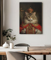 A majestic canvas portrait features a regal cat dressed as a king. The cat wears an ornate gold and red robe with intricate patterns and a luxurious red cape draped over its shoulders. On its head rests an elaborate golden crown adorned with jewels, and in one paw, the cat holds a royal scepter topped with a decorative cross. The cat's confident gaze and proud posture exude authority and nobility. The dark, softly lit background enhances the grandeur of the royal theme. Below the portrait, a wooden dining t